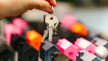 Jakub Zerdzicki Case colorate in miniatura e una mano con le chiavi rappresentano le decisioni immobiliari.